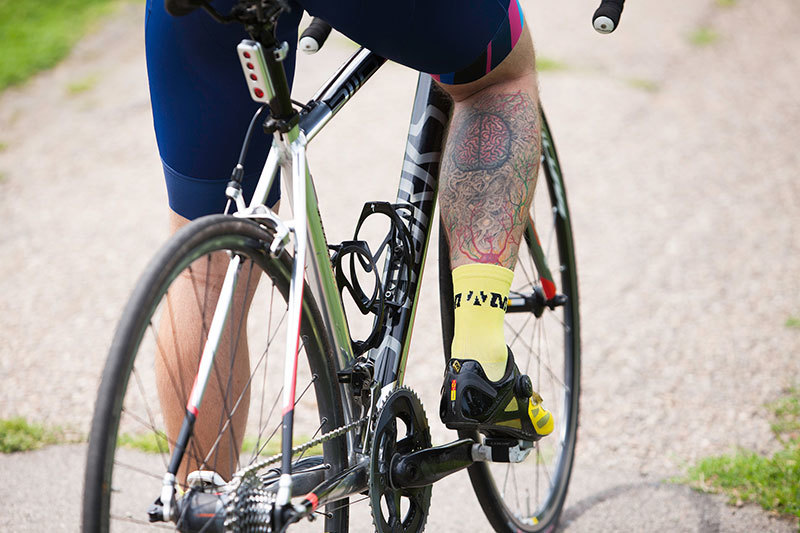 Craig Grad on bike with brain tattoo on his calf.