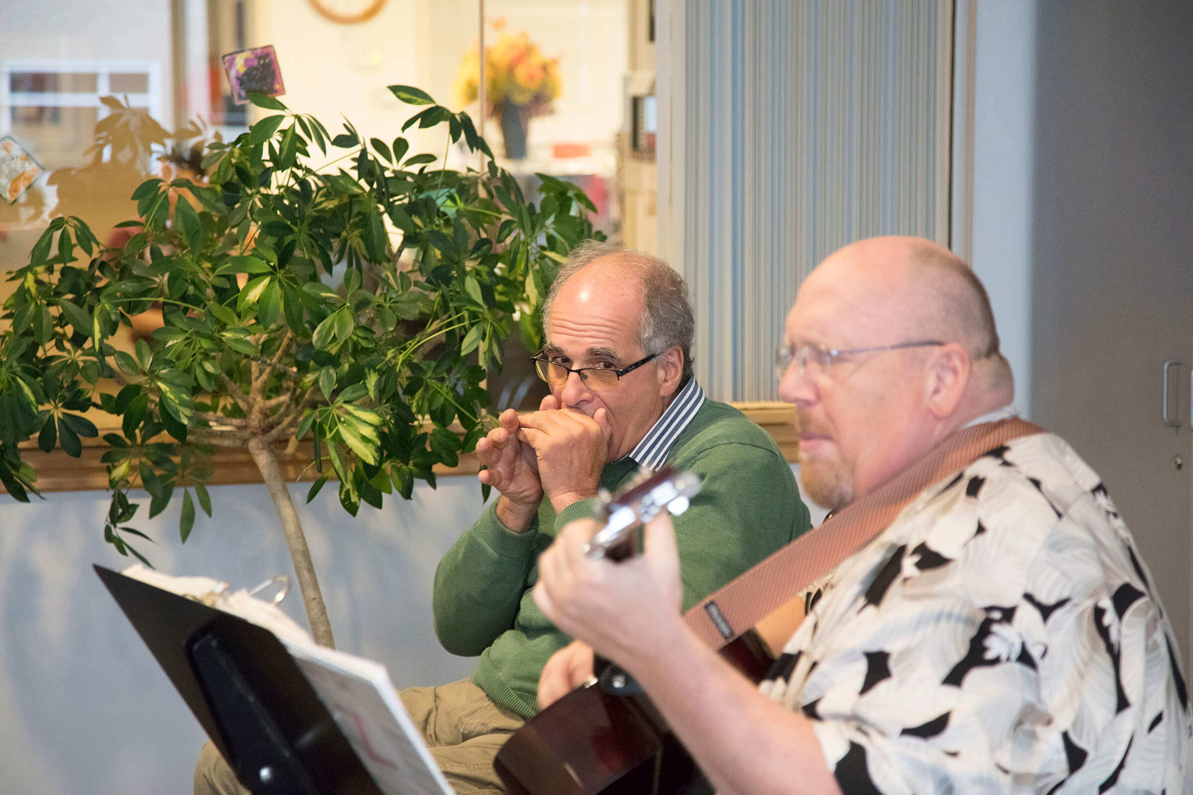 Jim Penta playing the harmonica while visiting Craig Hospital on Wish of a Lifetime trip years after spinal cord injury and traumatic brain injury rehabilitation