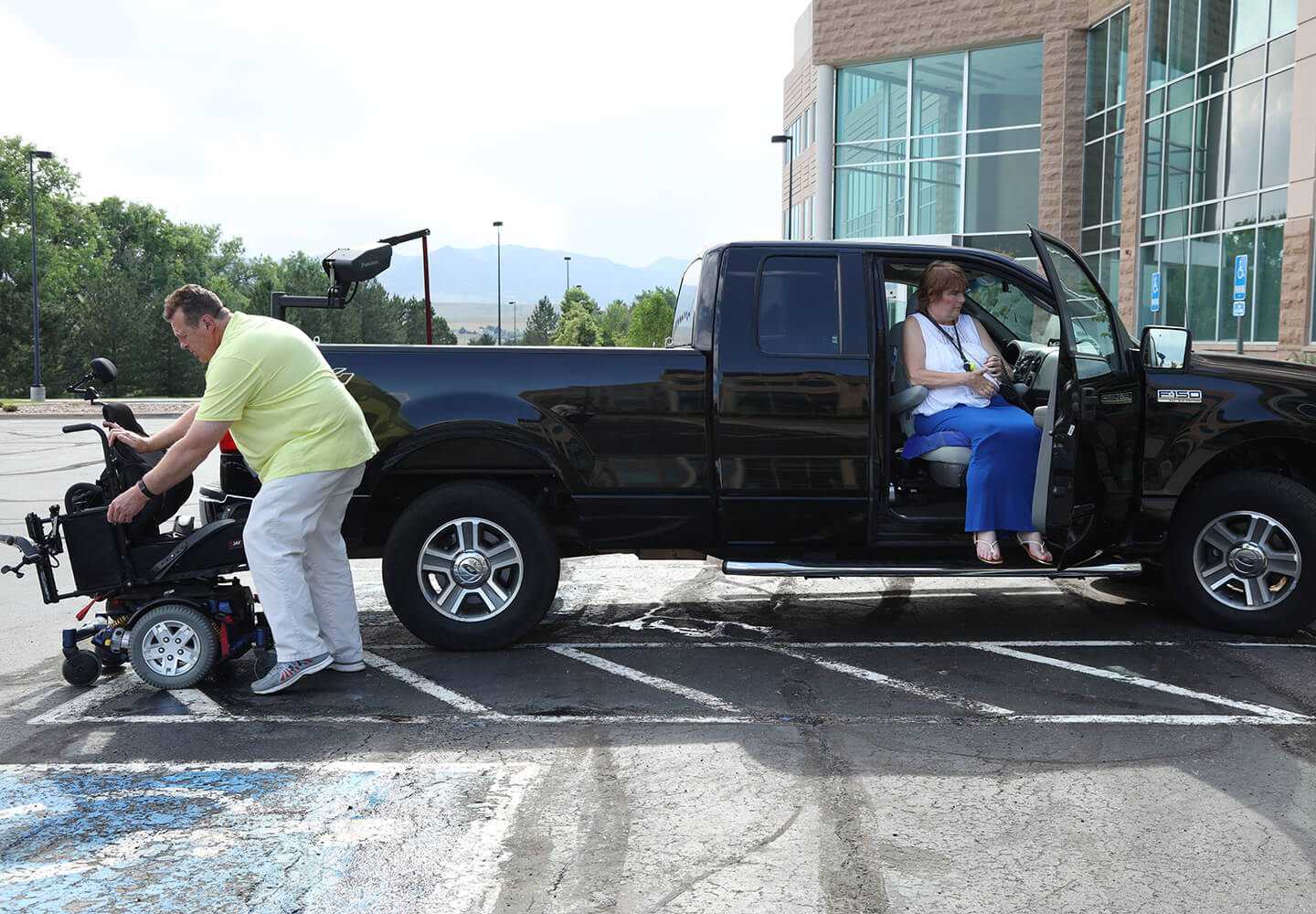 Shelly's husband gets her wheelchair out of their truck so that she can go into her office.
